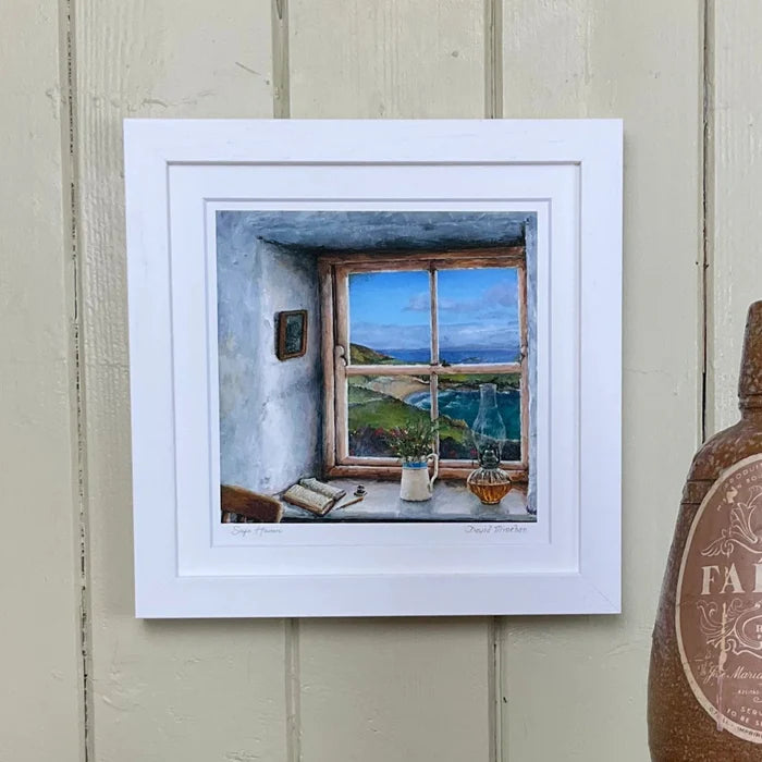 Framed artwork of a room with a window view on a wooden surface with a bottle labeled 'Paisca'.