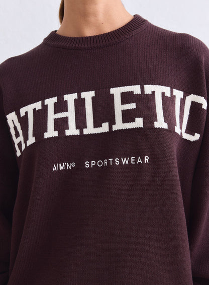 Lähikuva suklaanruskeasta aim'n Athletic Knit Sweatshirt -neulepaidasta valkoisella logolla [S-165cm]