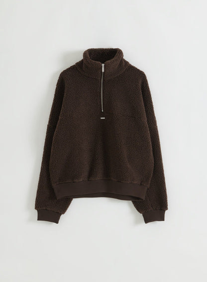 Suklaanruskea teddyfleece-pusero puolivetoketjulla aseteltuna tasolle