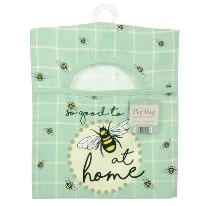 Peg bag with bee design and text 'So good to be at home' on a green checkered background.