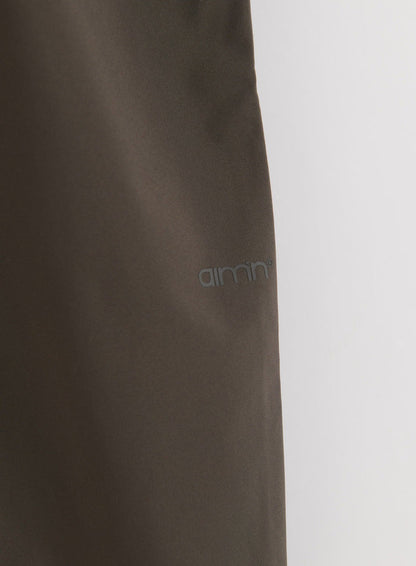 Lähikuva Dark Ivy Waterproof Pants -housujen kankaasta, jossa näkyy aim'n-logo