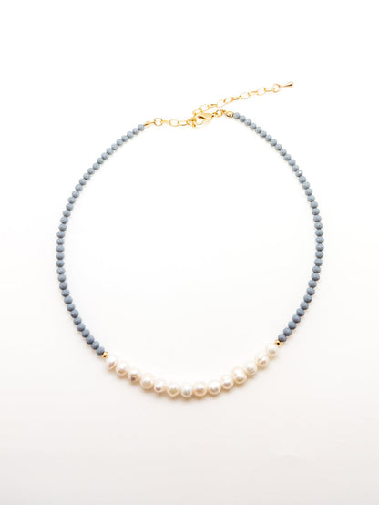 A dark blue beaded necklace with elegant white pearls, featuring an adjustable gold-colored chain.