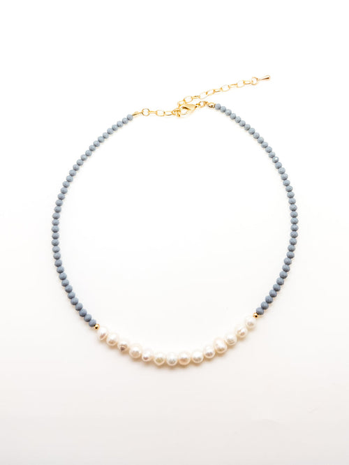 A dark blue beaded necklace with elegant white pearls, featuring an adjustable gold-colored chain.