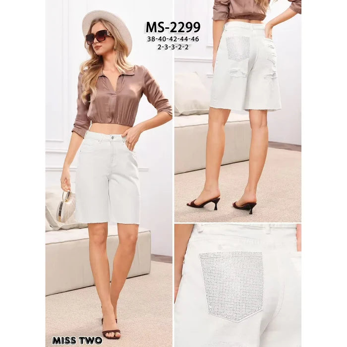 Ivory stretch denim Bermuda shorts featuring crystal embellished back pockets, subtle distressed patches, and raw hems.