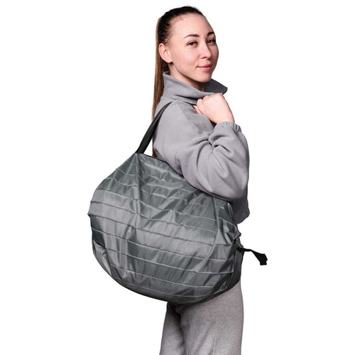 Woman carrying a grey quilted handbag on a white background