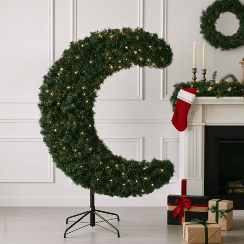 crescent moon shaped tree in contemporary room beside fireplace with gifts in front